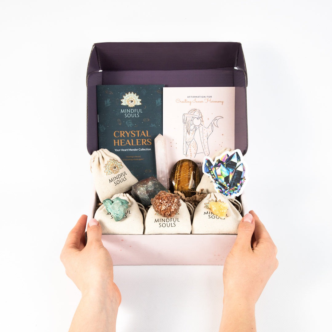 Mindful Souls crystal gift box featuring assorted healing stones, crystal guardians booklet, angel illustration card, and various crystals including amethyst, citrine, and black tourmaline arranged in an open purple box.