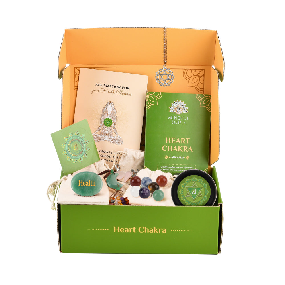 Open box containing heart chakra themed items with green and orange packaging.
